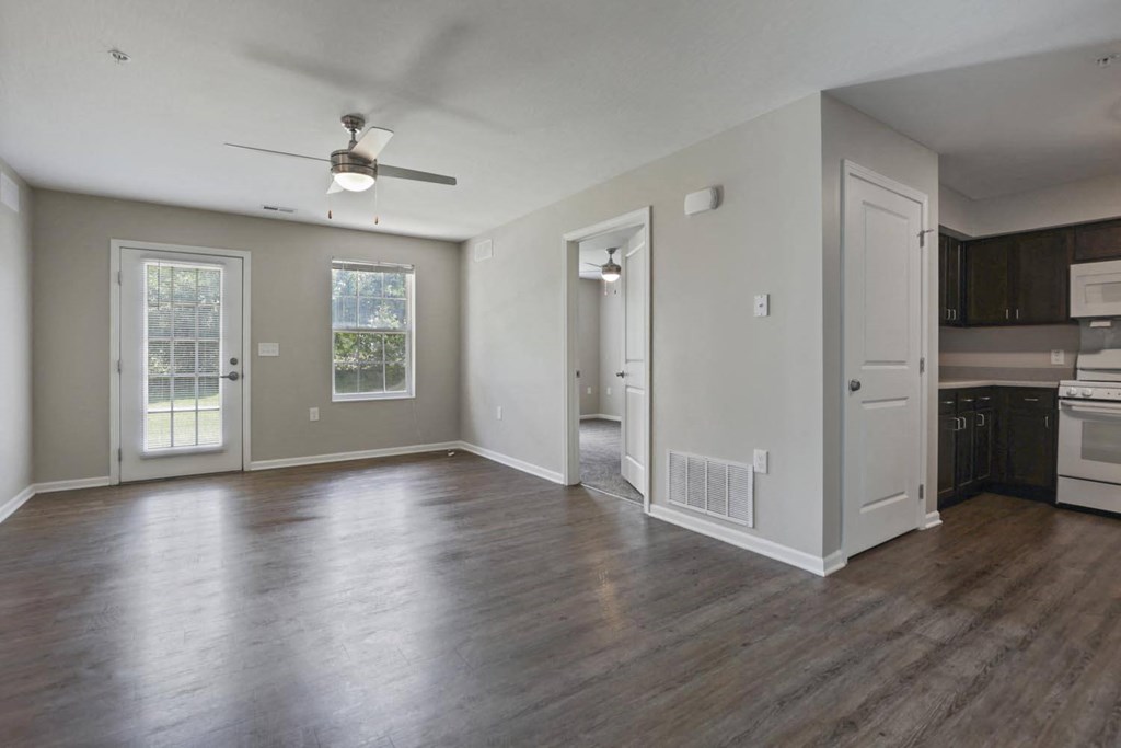 an empty living room and kitchen with wood floors and a ceiling fan