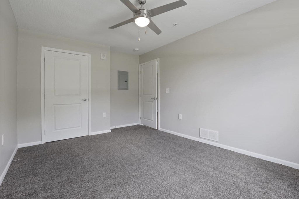 an empty living room with a ceiling fan