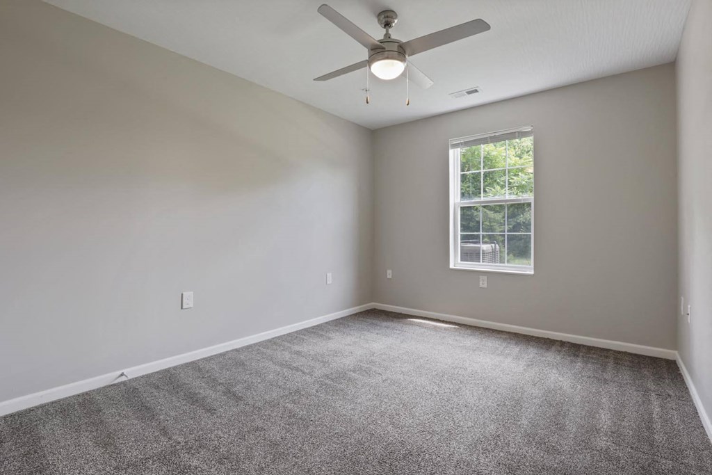 an empty room with a ceiling fan and a window