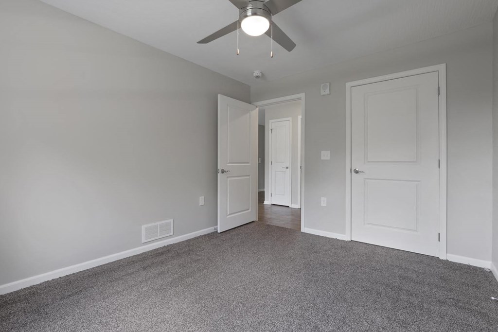 a bedroom with a ceiling fan and a door to a hallway