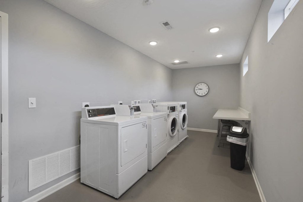 a laundry room with four washes and a clock on the wall