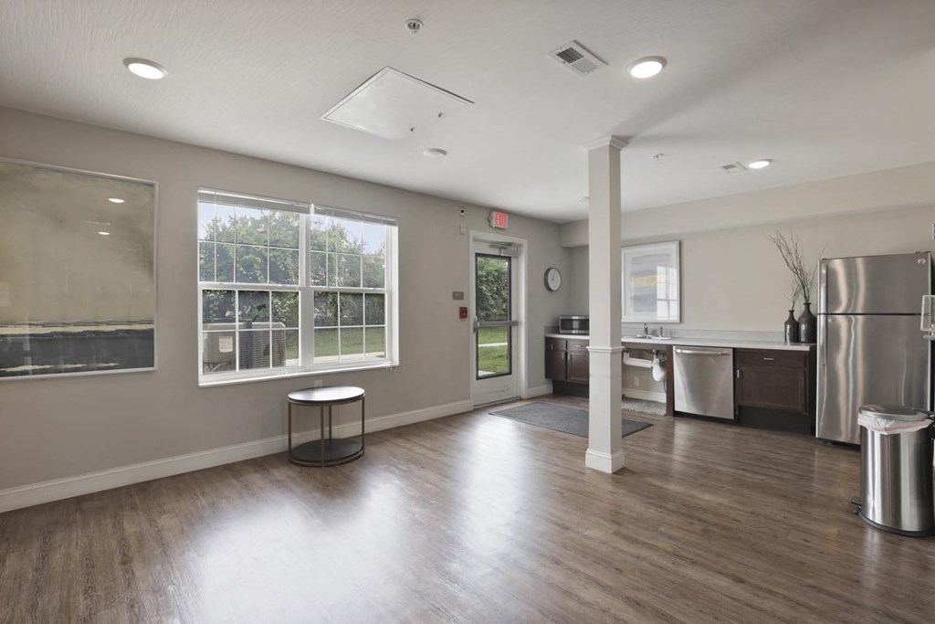an empty living room with a kitchen and a large window