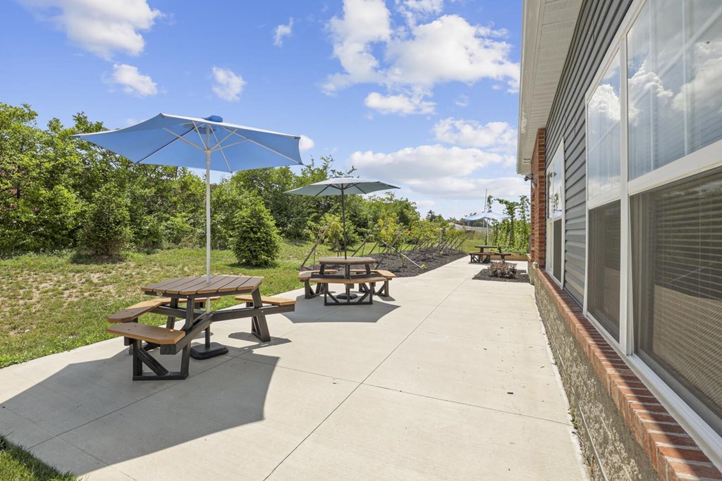 the patio outside of the building has picnic tables and umbrellas