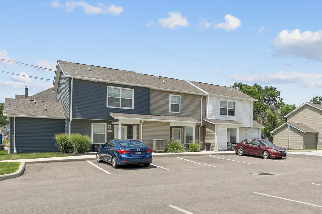 two cars parked in a parking lot in front of a house