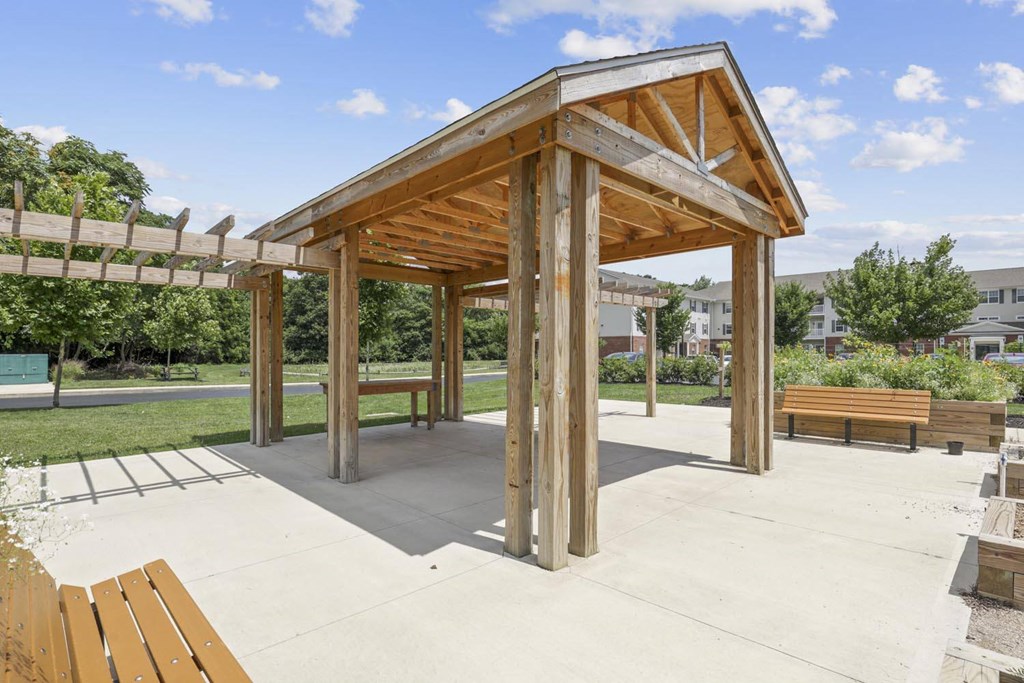 a covered picnic area with benches in a park