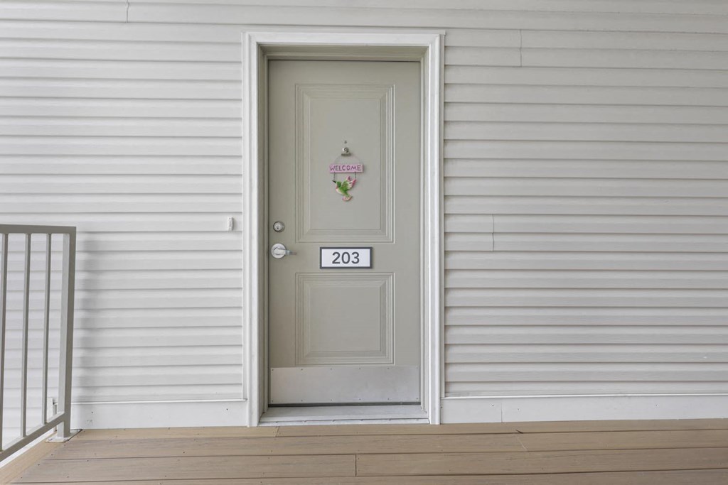 the front door of a white house with a gray door