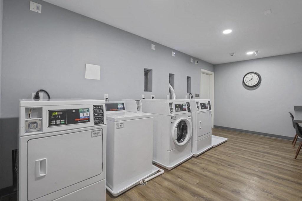 a group of washes and dryers in a room with a clock