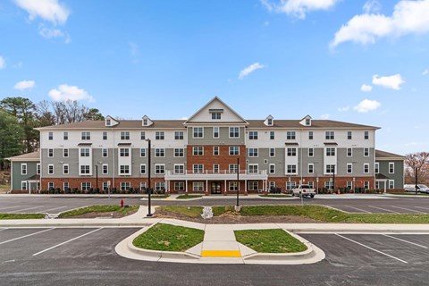 A large apartment complex with a parking lot in front.