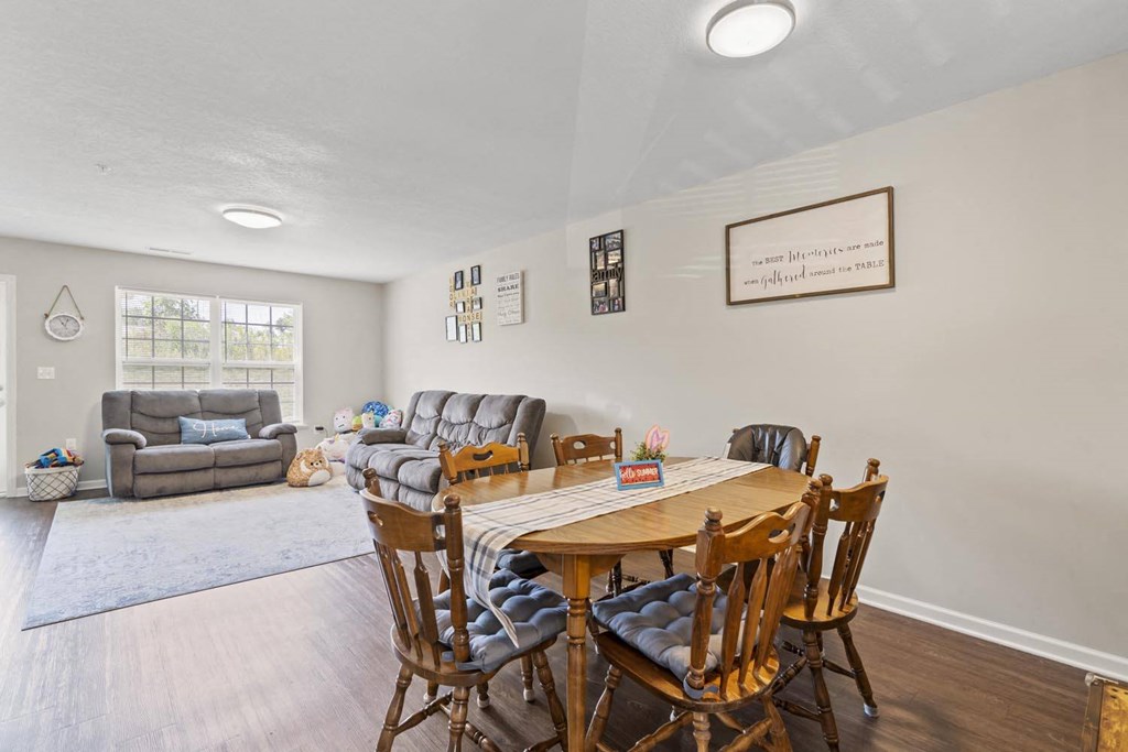 a dining area with a table and chairs and a couch in the background