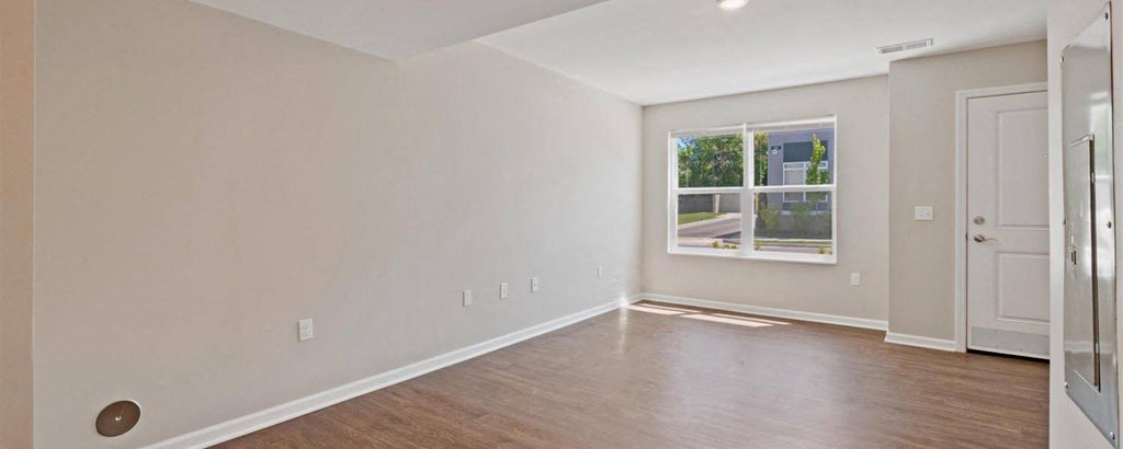 an empty living room with a window and wood floors