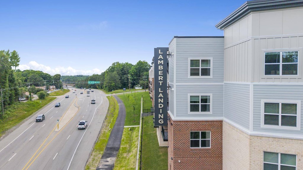 A street with cars and a building with a sign that says "Lambert Landing" on it.