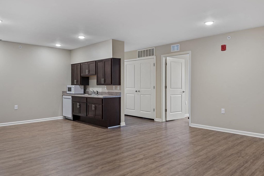 an empty living room with a kitchen and a door way