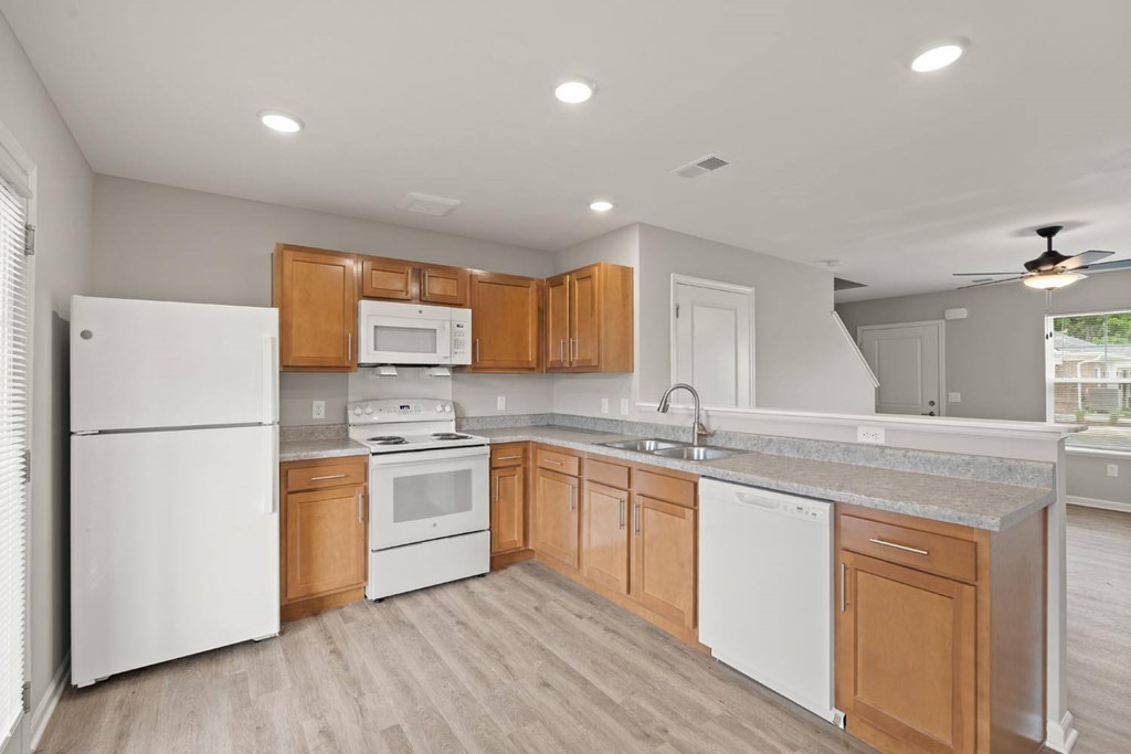 A kitchen with white appliances and wooden cabinets.