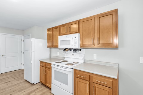 A kitchen with white appliances and wooden cabinets.