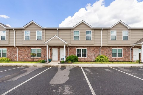 the front of a brick apartment building with a parking lot