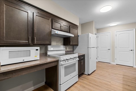 A kitchen with white appliances and brown cabinets.