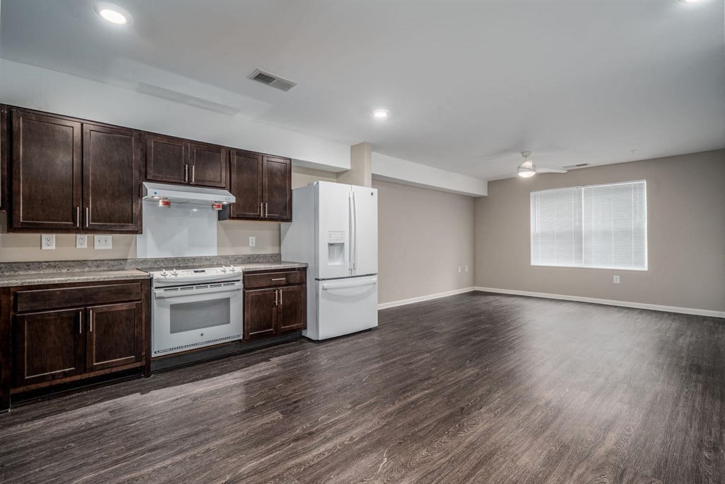 an empty kitchen with white appliances and wooden cabinets
