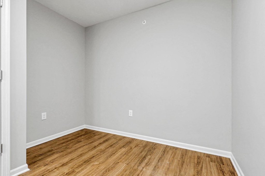 an empty room with wooden floors and grey walls