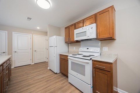 A kitchen with a white stove and a white microwave above it.