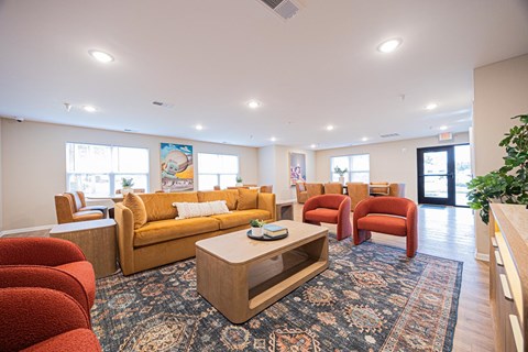 A living room with a yellow couch and red chairs.