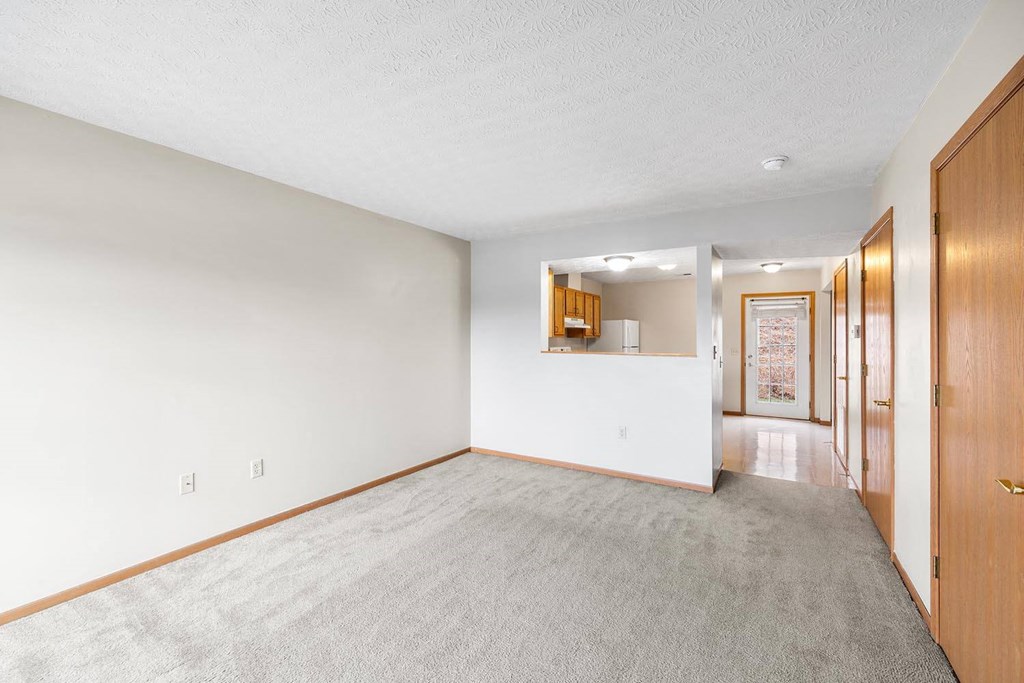 a living room with a carpeted floor and a hallway to a kitchen