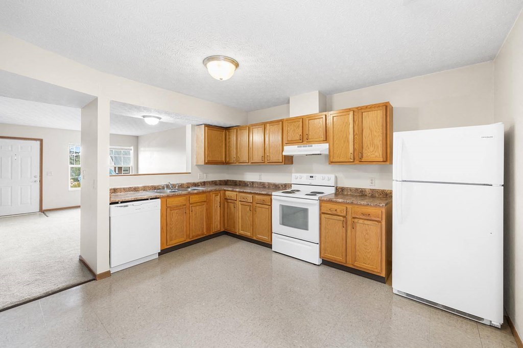 an empty kitchen with white appliances and wooden cabinets