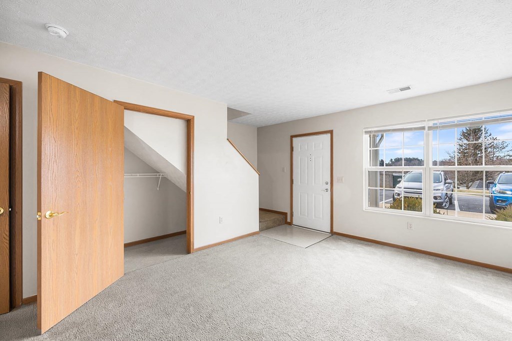 an empty living room with a door and a window