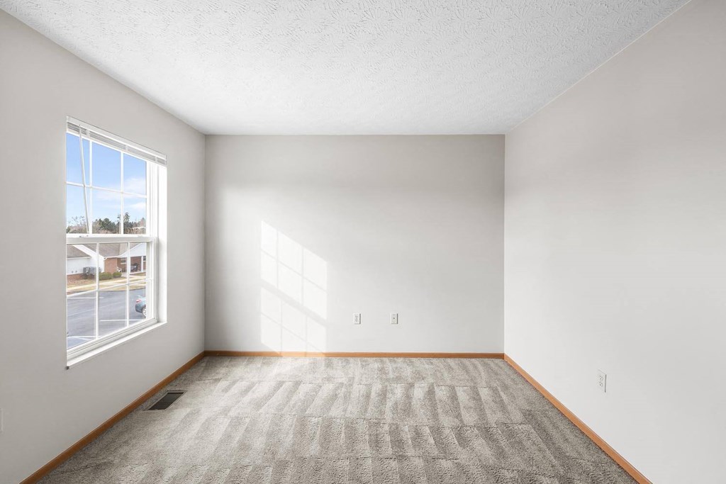 an empty room with a window and carpet