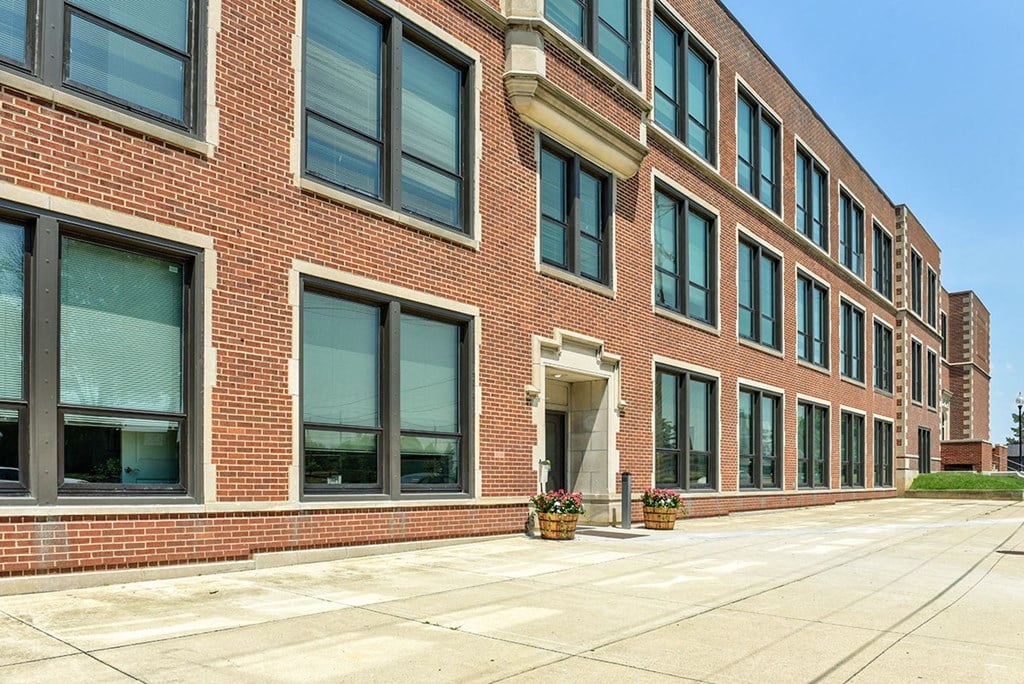 a large brick building with large windows and a sidewalk