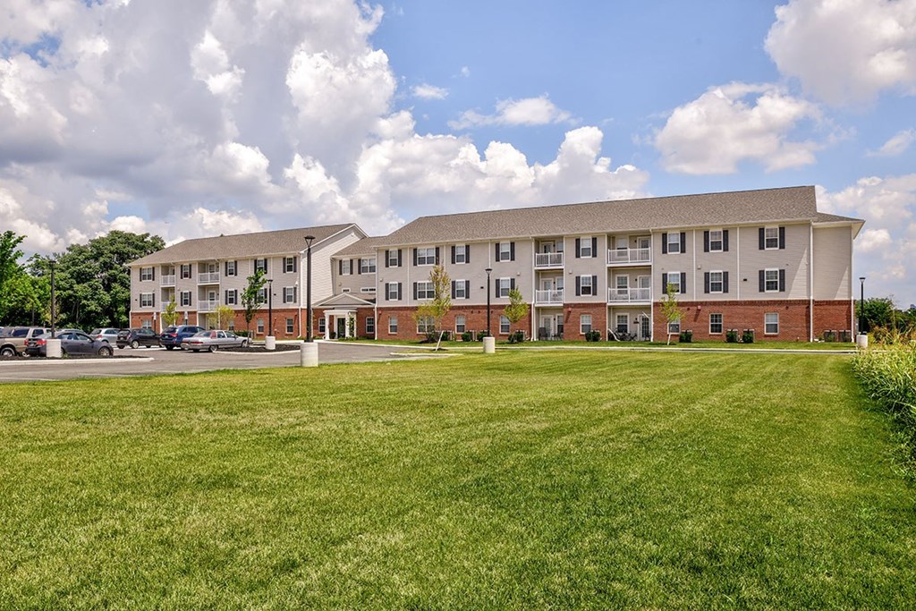 A large apartment complex with a grassy field in front.