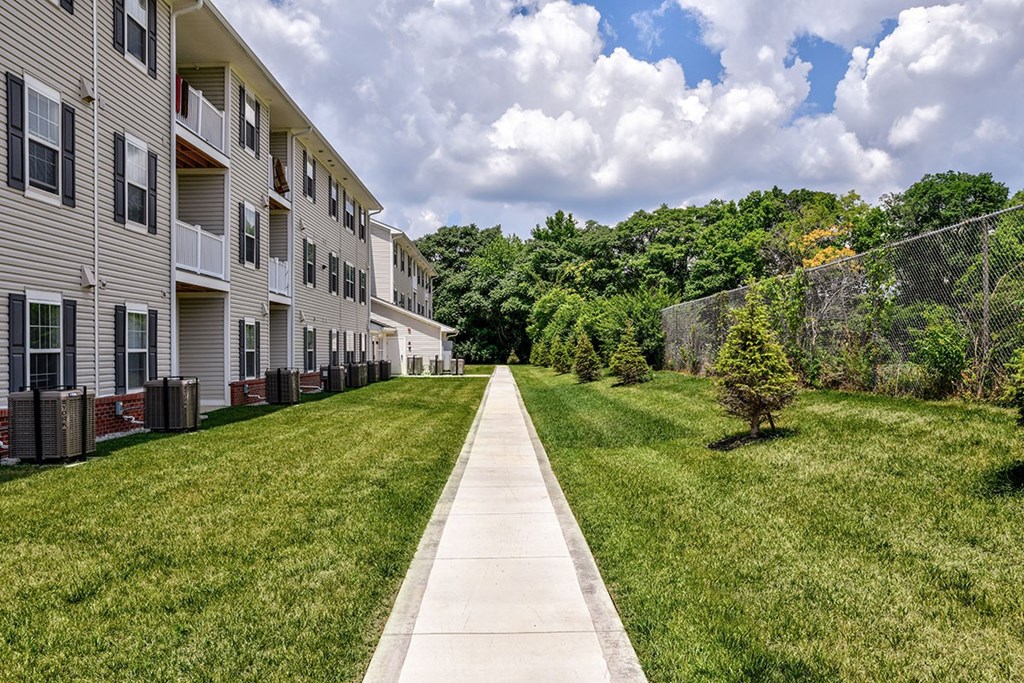 A long concrete walkway leads between apartment buildings.