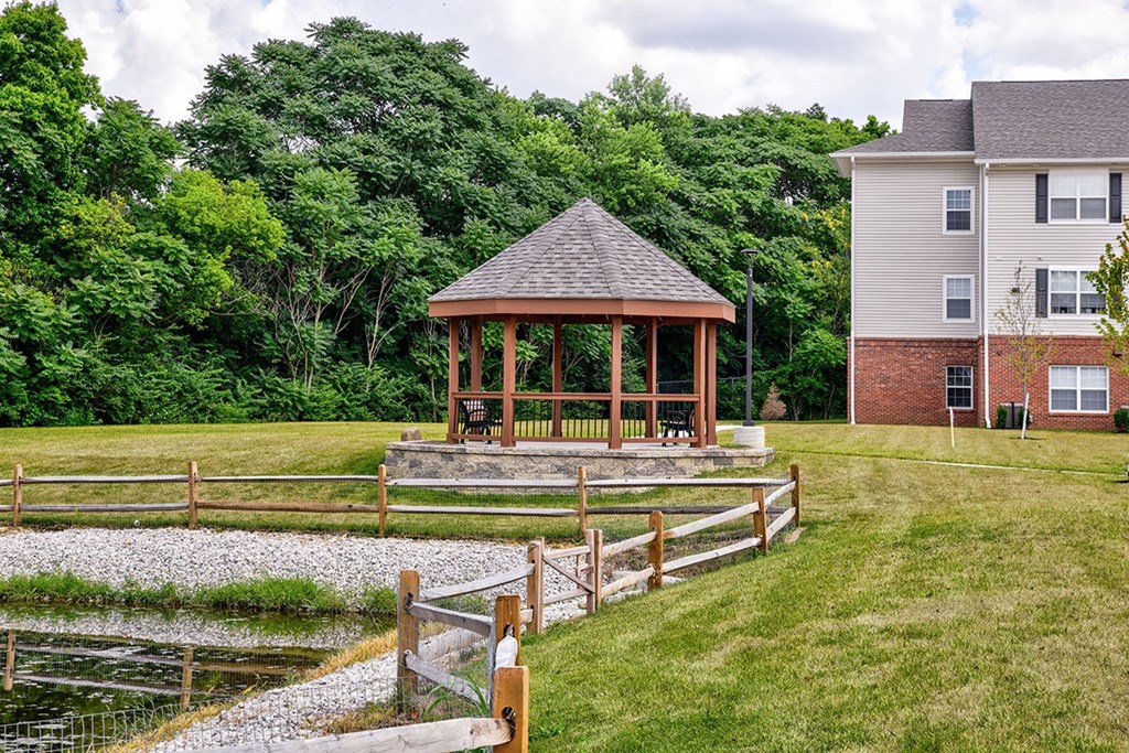 A gazebo is situated in a grassy area in front of a house.