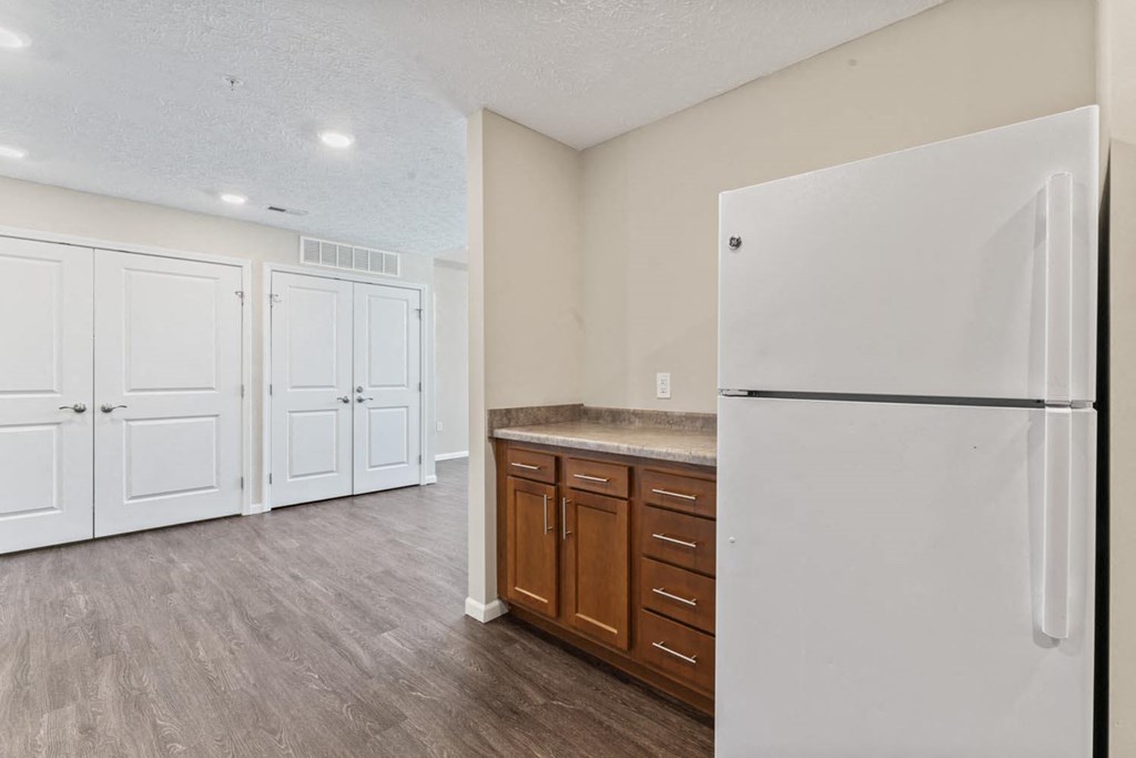 an empty kitchen with a refrigerator and cabinets