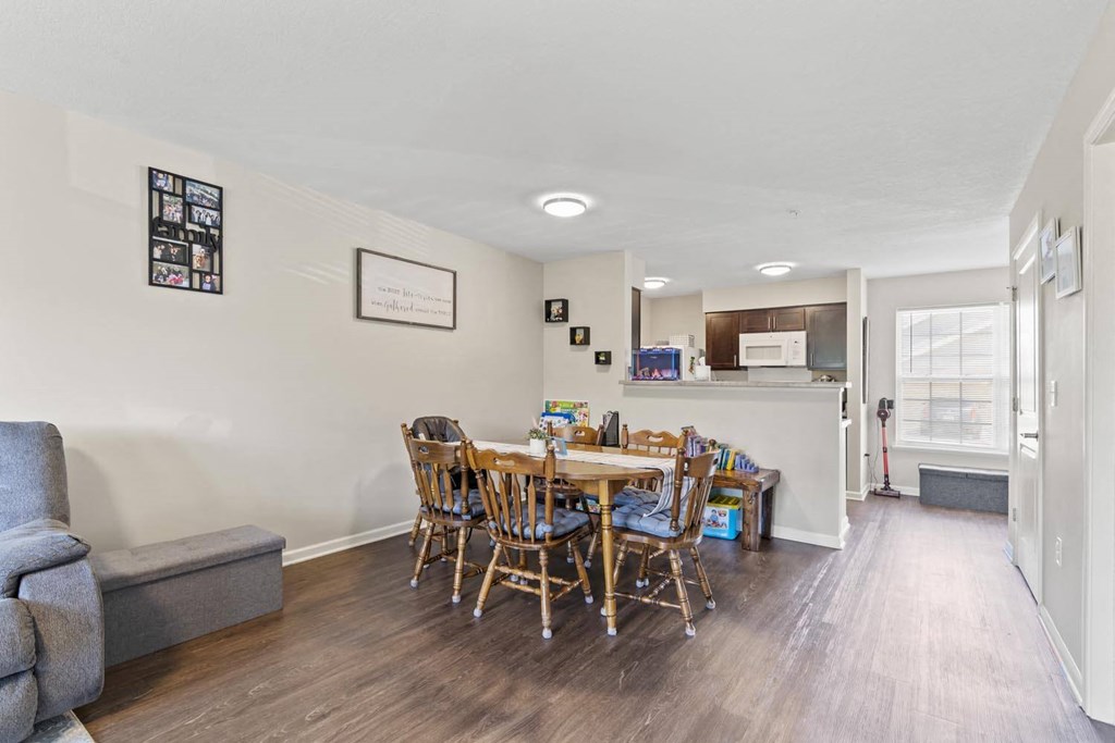 a dining area with a table and chairs and a kitchen in the background