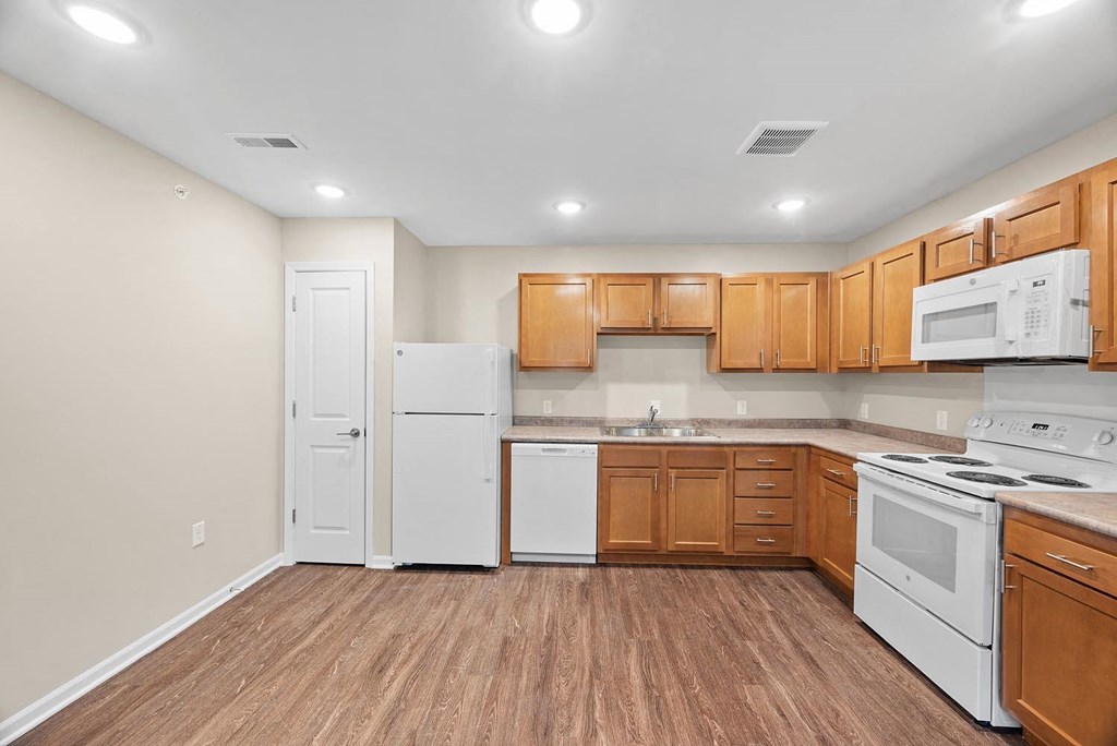 A kitchen with white appliances and wooden cabinets.