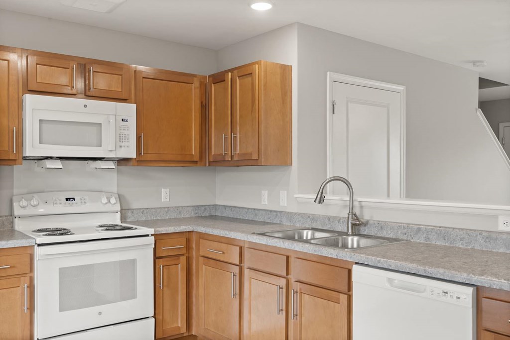 A kitchen with a white stove, white microwave, and white dishwasher.