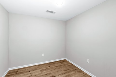 A room with wooden flooring and white walls.