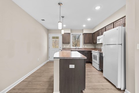 A kitchen with a white refrigerator and wooden island.