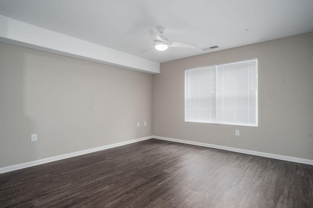 an empty living room with wood floors and a window