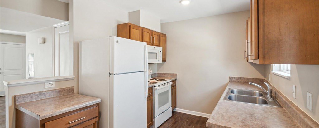 A kitchen with a white refrigerator and wooden cabinets.