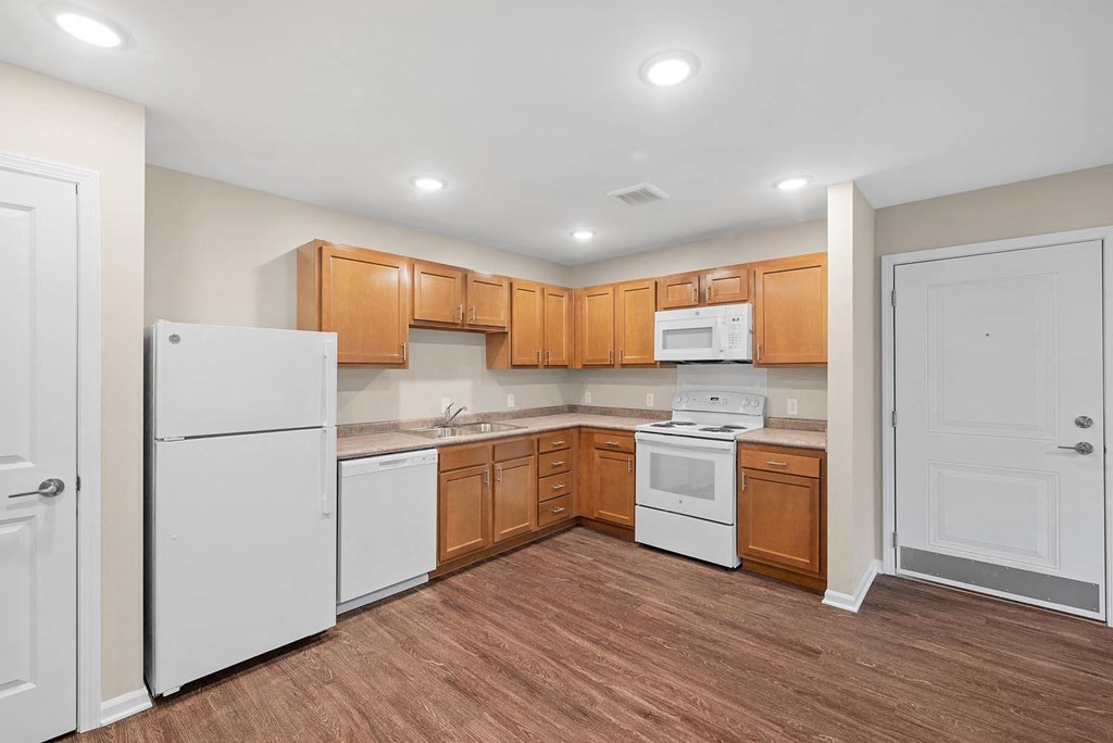 A kitchen with white appliances and wooden cabinets.