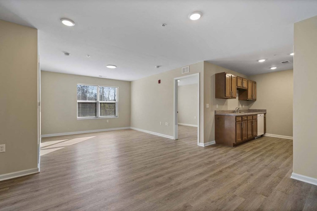 an empty living room and kitchen with wood floors