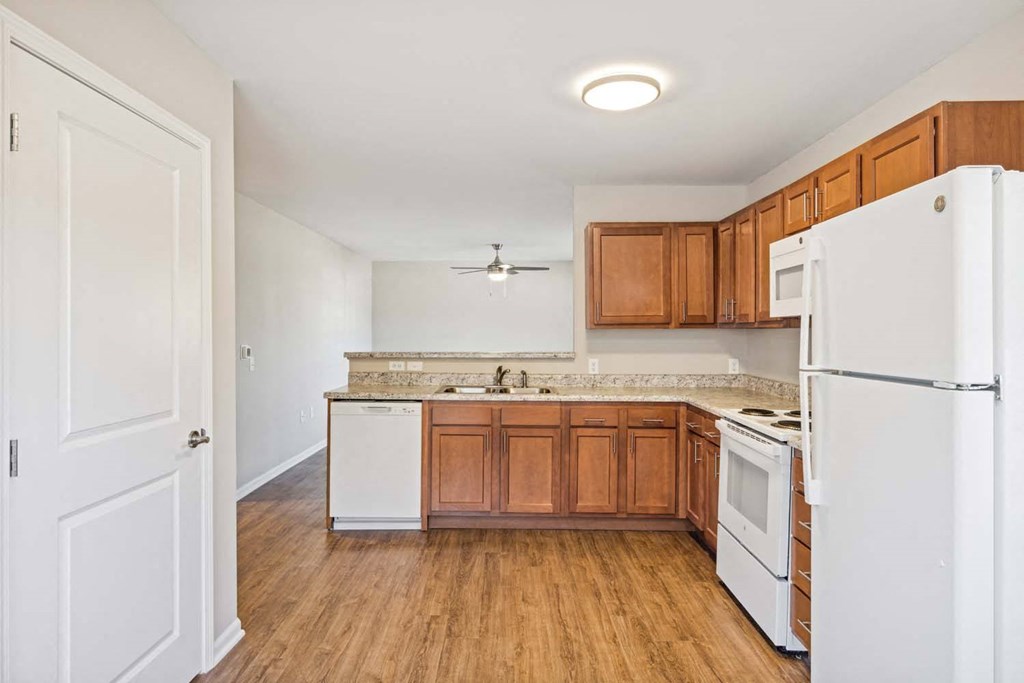 an empty kitchen with white appliances and wooden cabinets