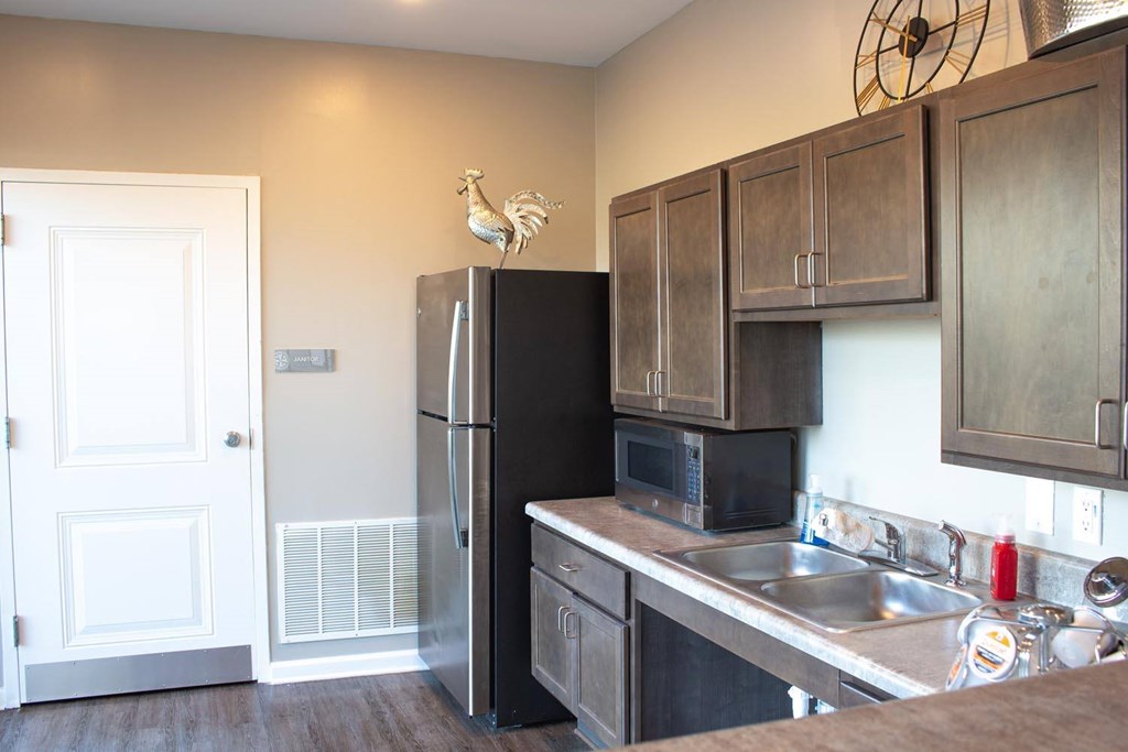 A kitchen with a black fridge and wooden cabinets.