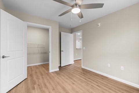 A room with a ceiling fan and two open doors.