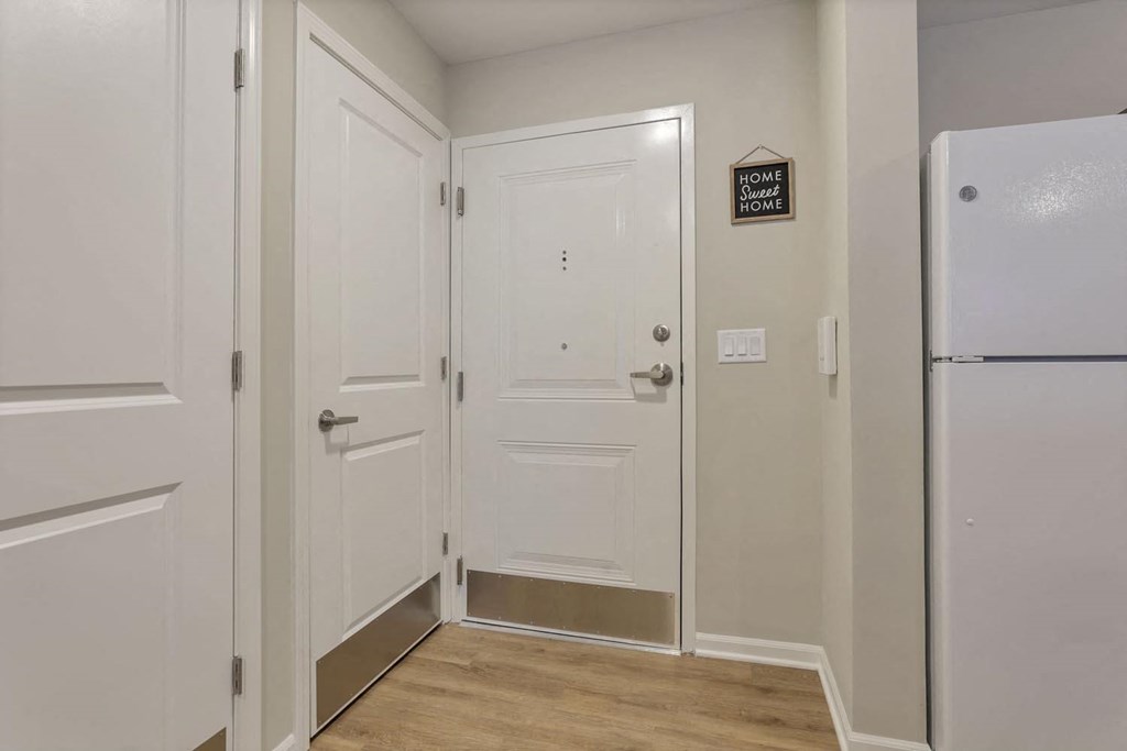 a hallway with white doors and a refrigerator