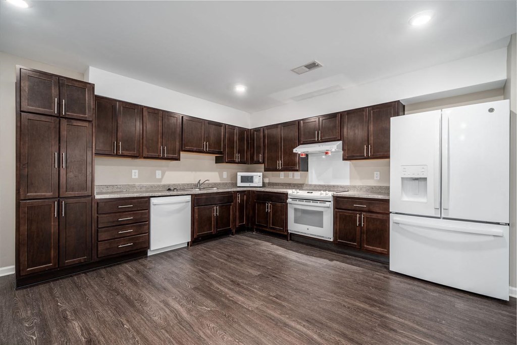 a kitchen with white appliances and dark wood cabinets