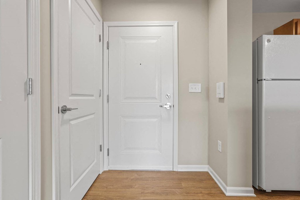 a hallway with white doors and a refrigerator