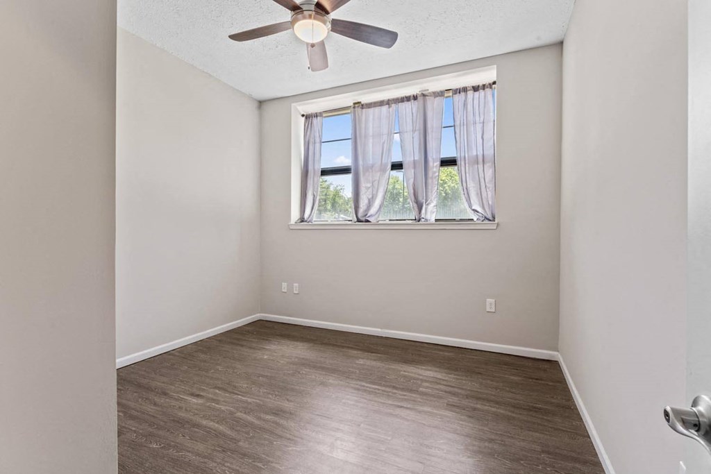 an empty room with a window and a ceiling fan