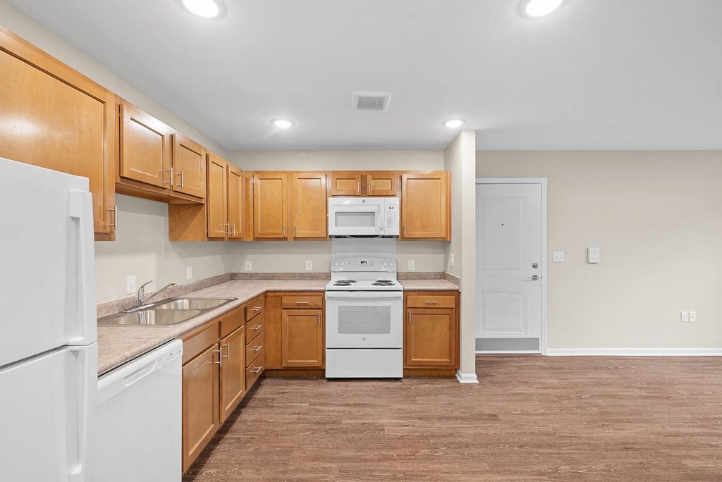 A kitchen with white appliances and wooden cabinets.